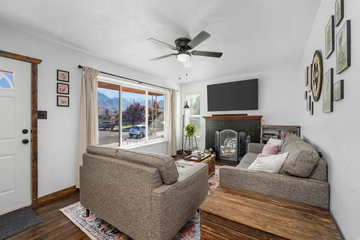 Living area featuring a fireplace, dark wood finished floors, a textured ceiling, and ceiling fan