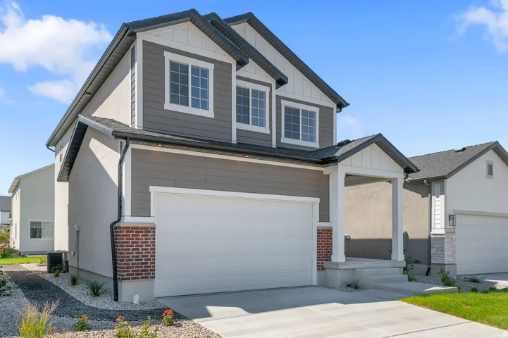 Craftsman-style home featuring board and batten siding, an attached garage, driveway, and brick siding