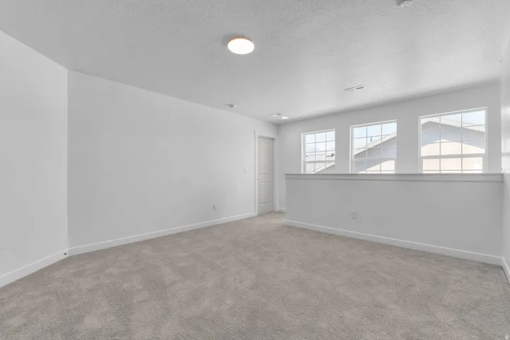 Spare room featuring light colored carpet and a textured ceiling