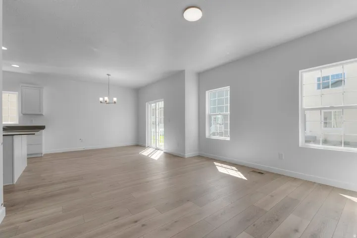 Unfurnished dining area with light wood-style floors, hanging lights, and a textured ceiling