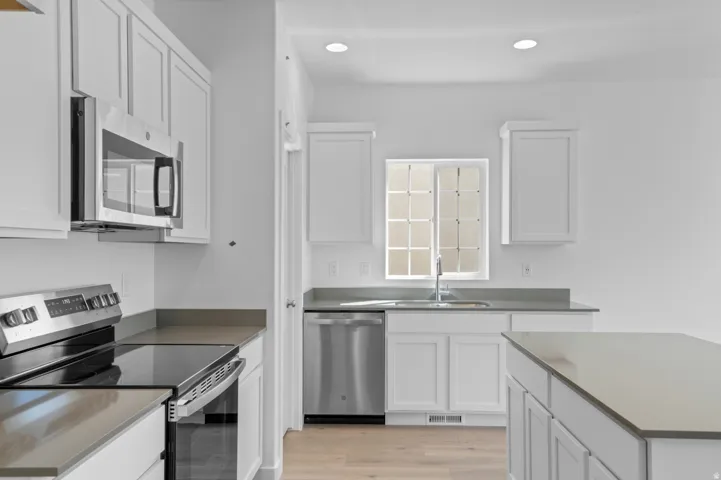 Kitchen featuring stainless steel appliances, white cabinetry, and light wood-style floors