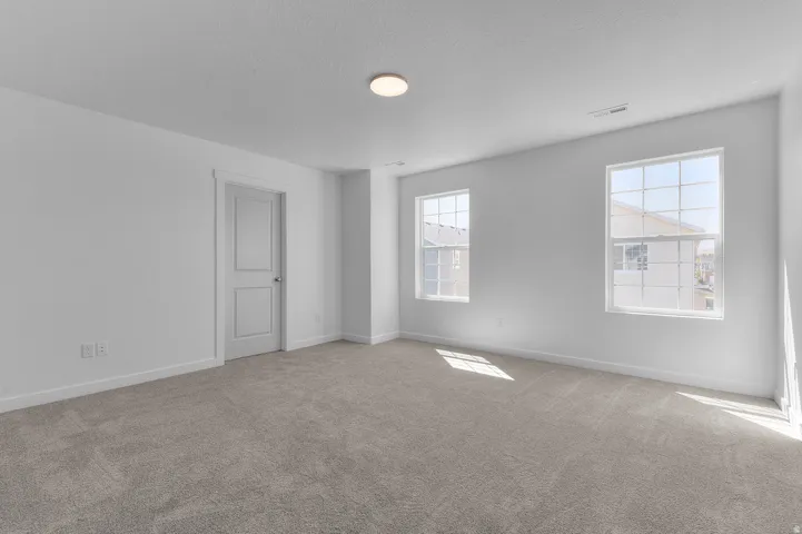 Unfurnished room featuring baseboards and light carpet