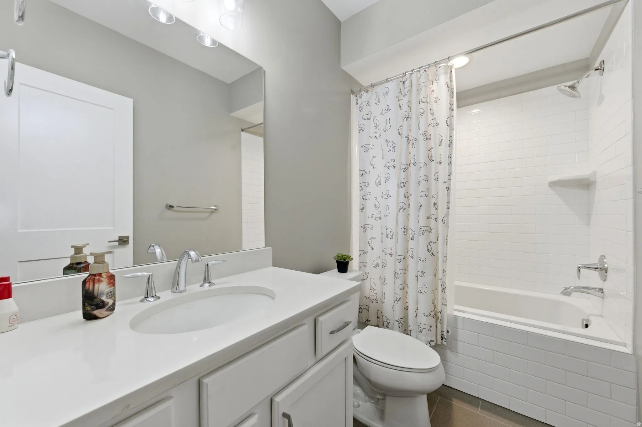 Bathroom with tiled shower / bath, vanity, and dark tile patterned floors