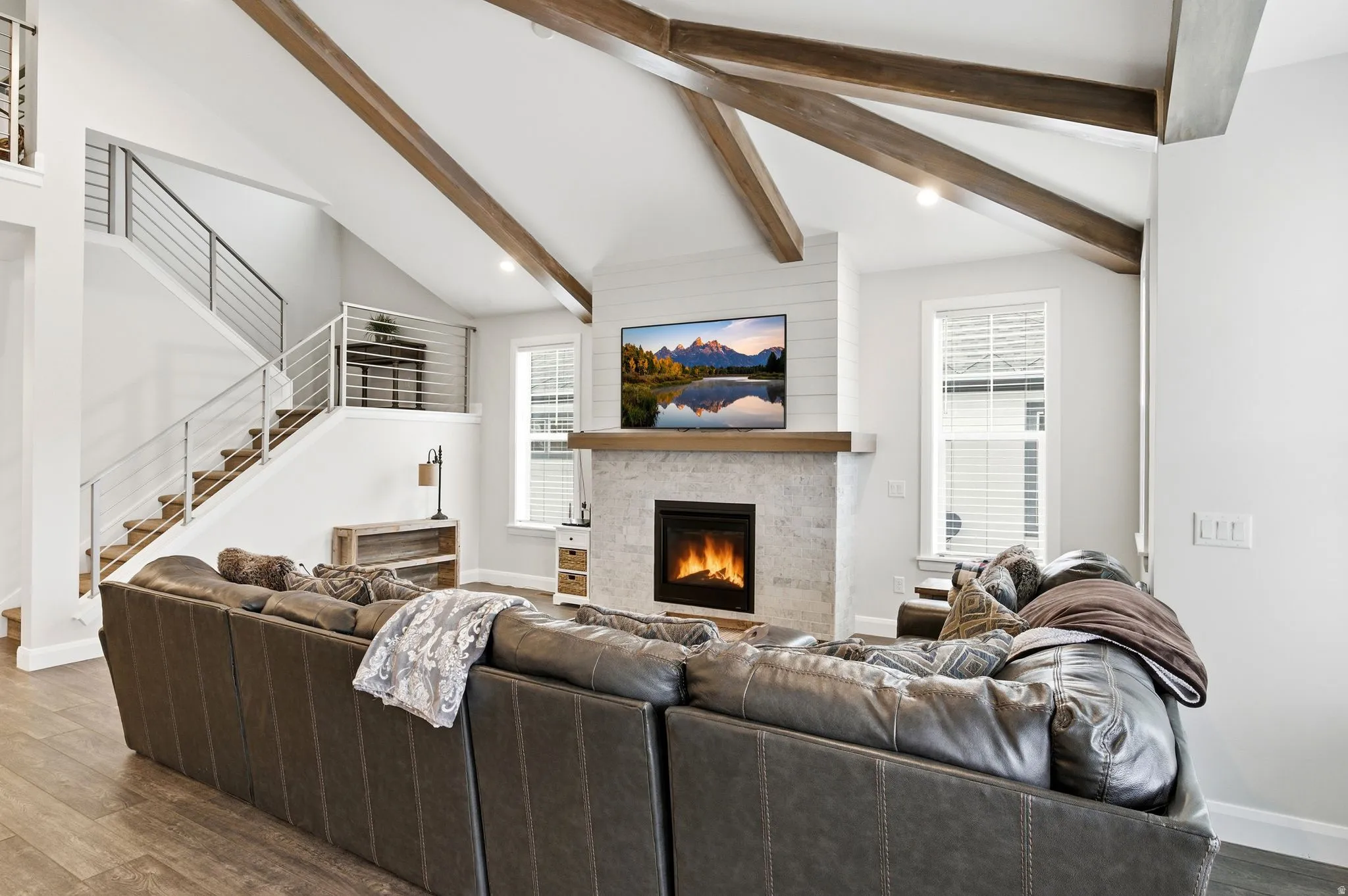 Living area featuring wood finished floors, vaulted ceiling with beams, a large fireplace, and recessed lighting