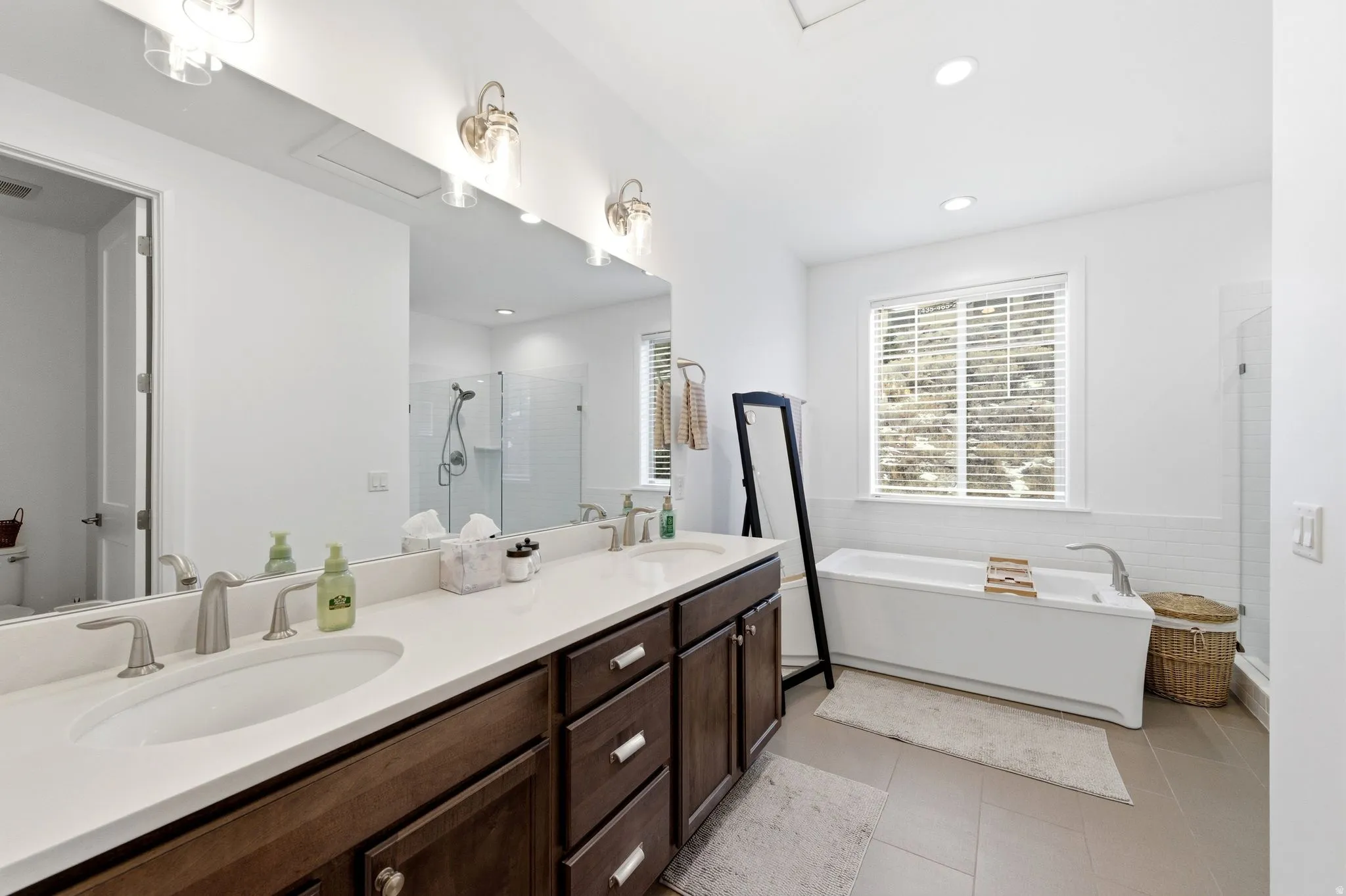 Full bathroom with a shower stall, double vanity, a freestanding bath, recessed lighting, and light tile patterned flooring