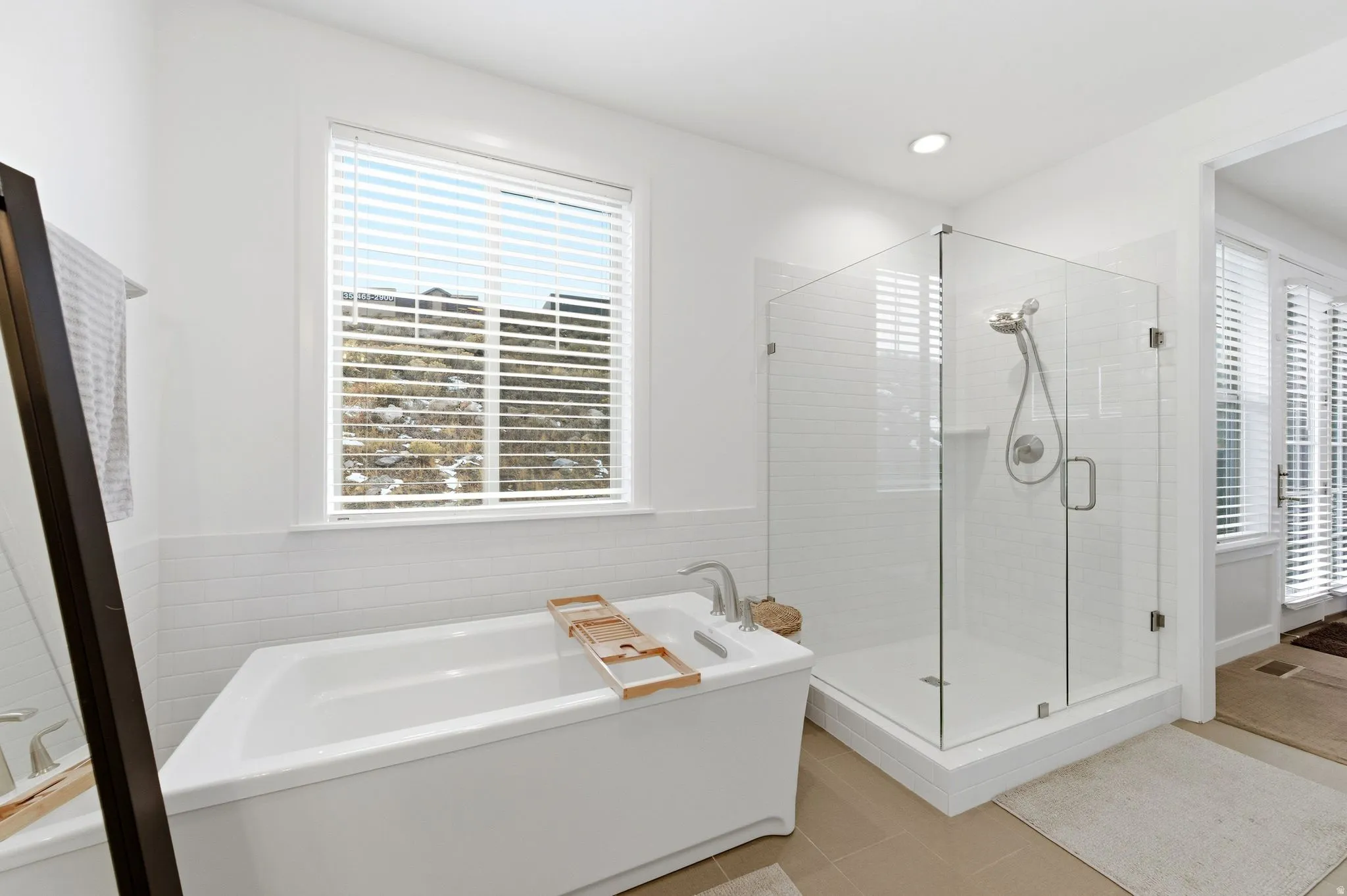 Bathroom featuring a freestanding bath, a stall shower, light tile patterned floors, and tile walls