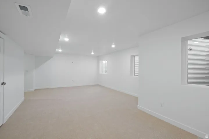 Below grade area with light colored carpet and recessed lighting