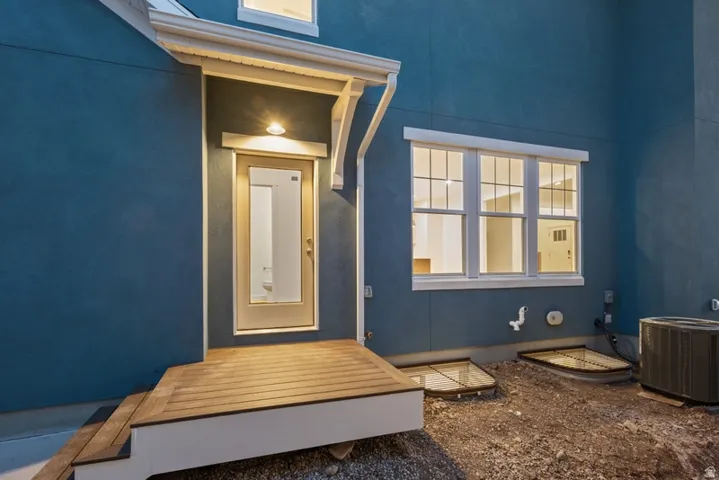 View of exterior entry featuring a wooden deck and stucco siding