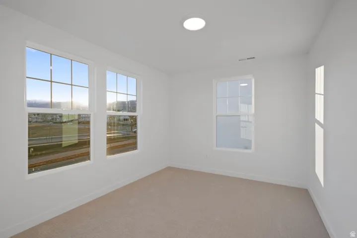 Empty room featuring light colored carpet and baseboards