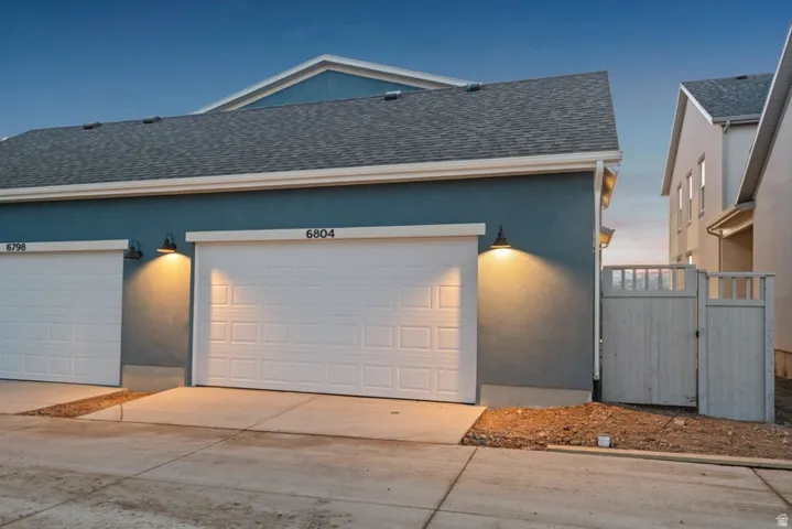 View of front of property with a shingled roof, stucco siding, and driveway