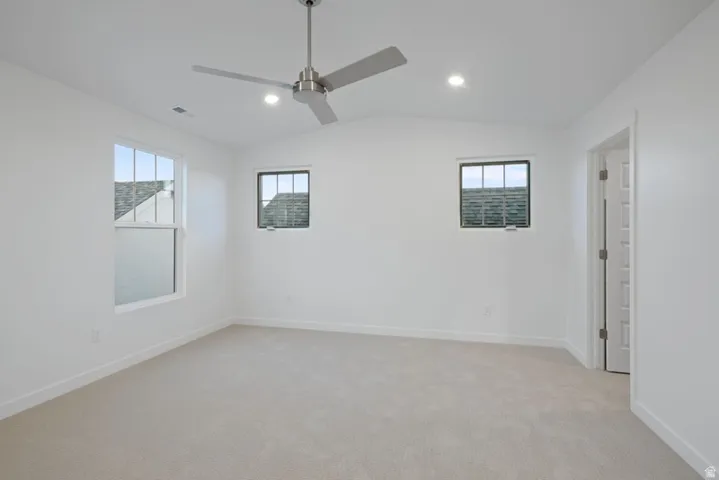 Unfurnished room featuring light colored carpet, lofted ceiling, recessed lighting, and ceiling fan