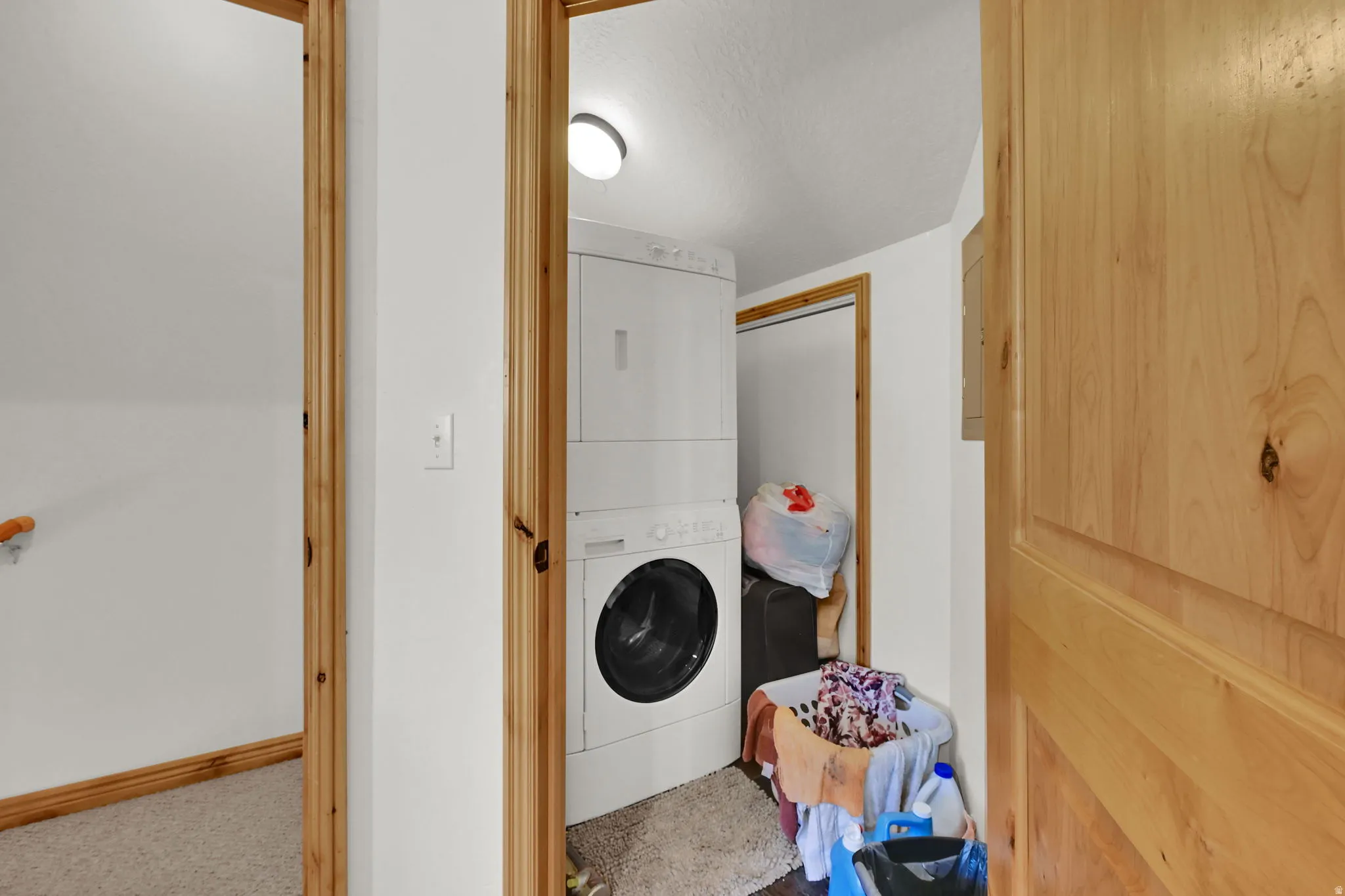 Laundry area featuring stacked washing machine and dryer and a textured ceiling