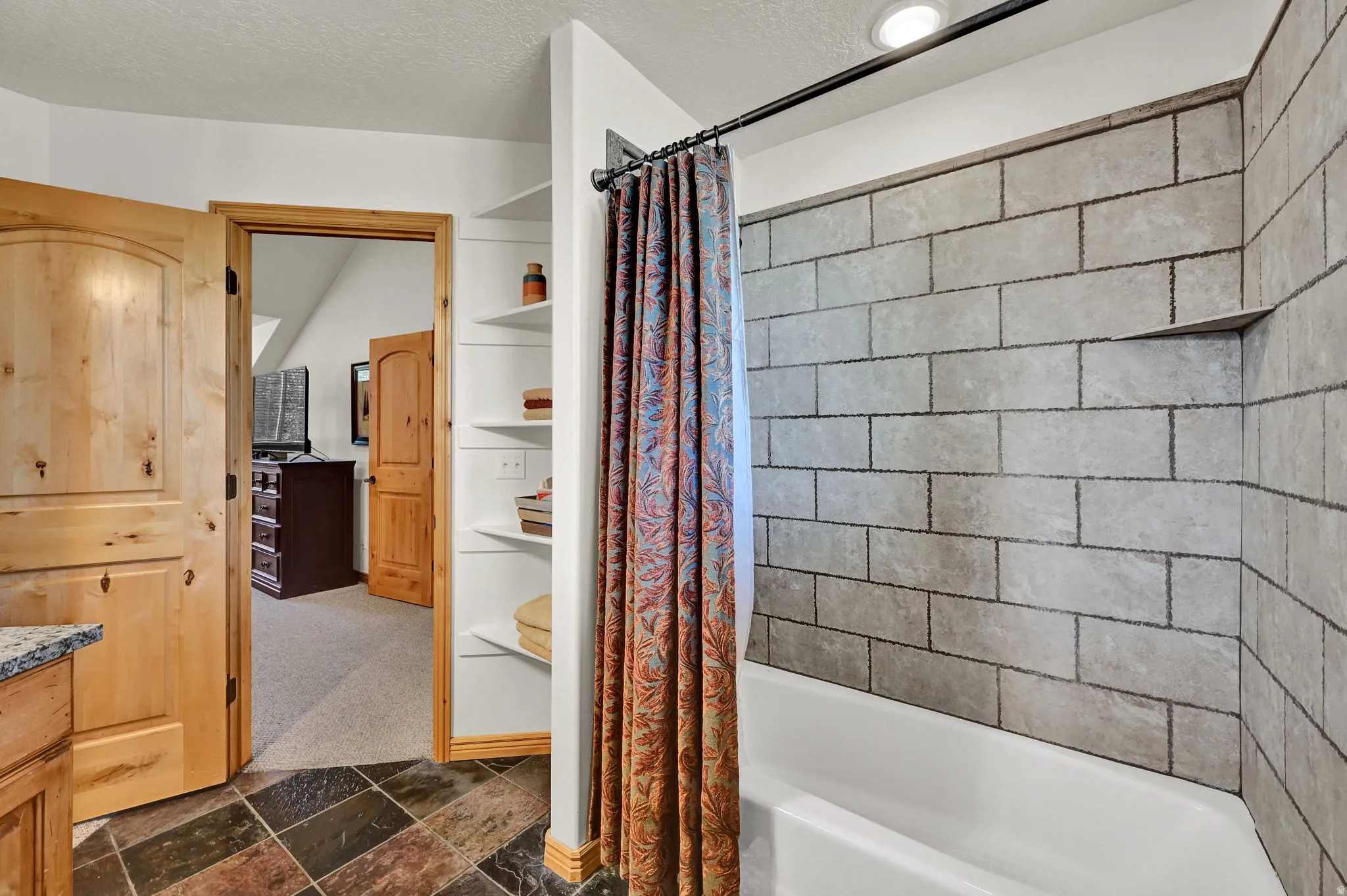 Bathroom with shower / tub combo with curtain, a textured ceiling, dark stone finish flooring, dark carpet, and vanity