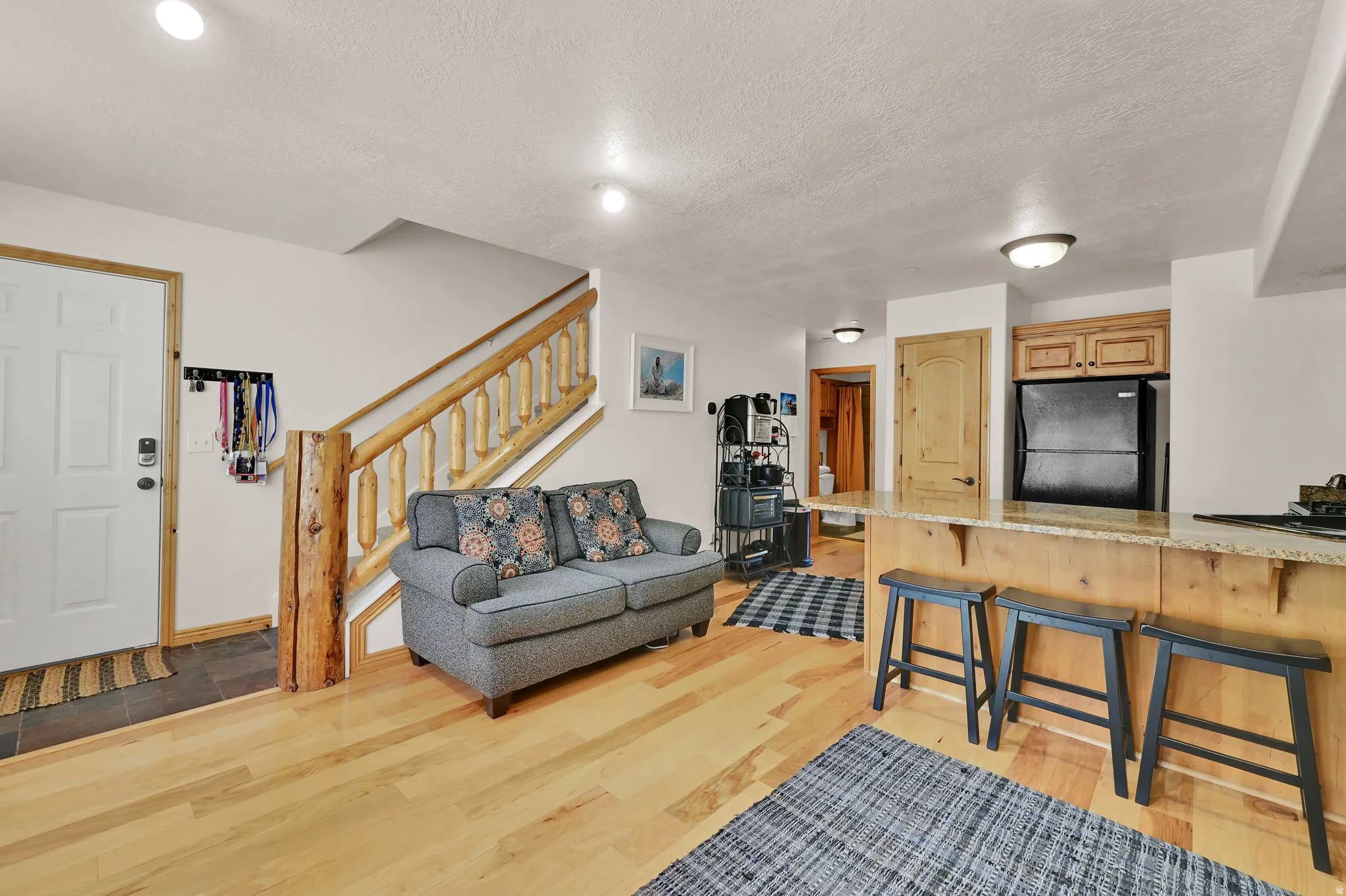 Living area with light wood-type flooring and a textured ceiling