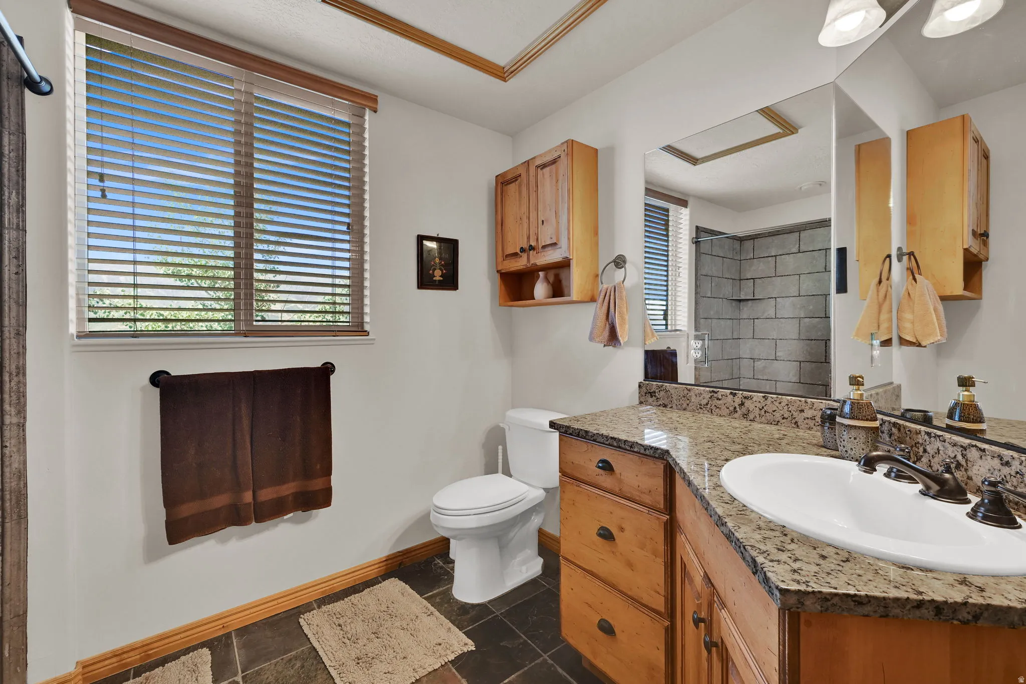 Full bathroom with tiled shower, vanity, and healthy amount of natural light