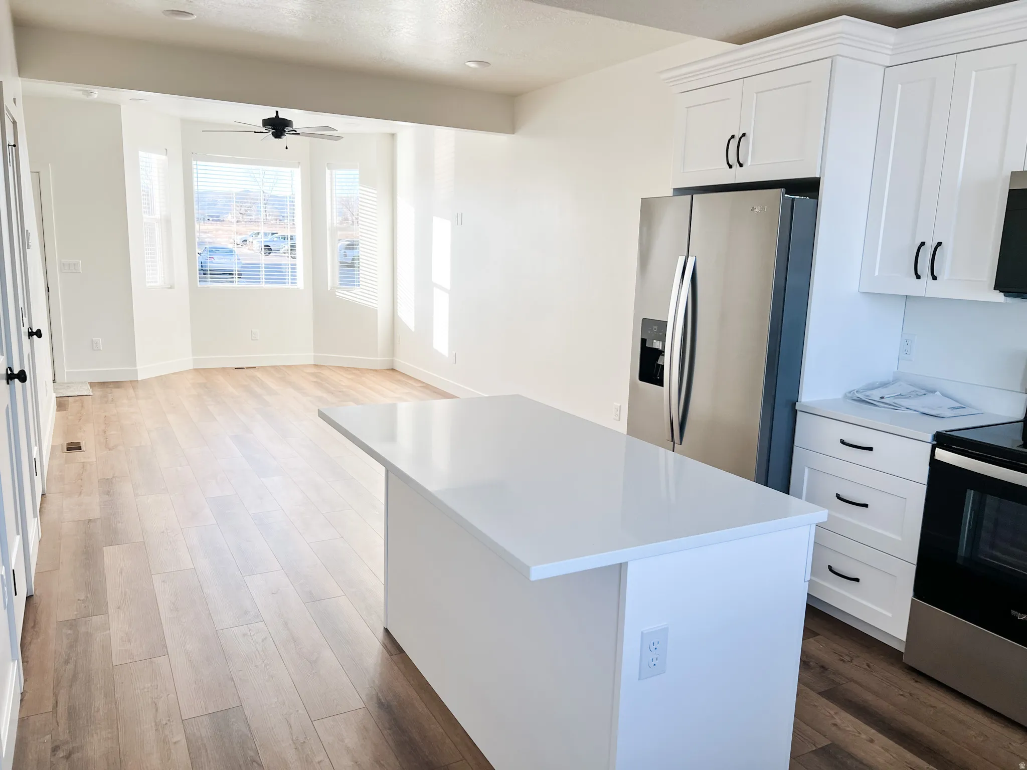 Kitchen with stainless steel appliances, white cabinets, dark wood finished floors, a center island, and ceiling fan