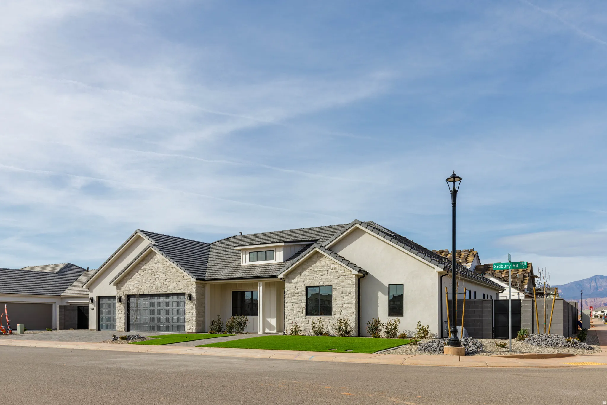 View of front facade with stone siding, an attached garage, stucco siding, a porch, and driveway