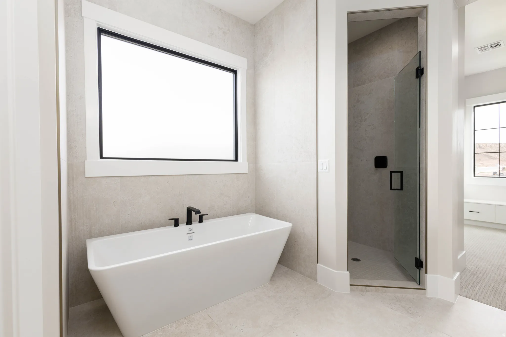 Bathroom featuring a freestanding tub, a shower stall, and light tile patterned flooring