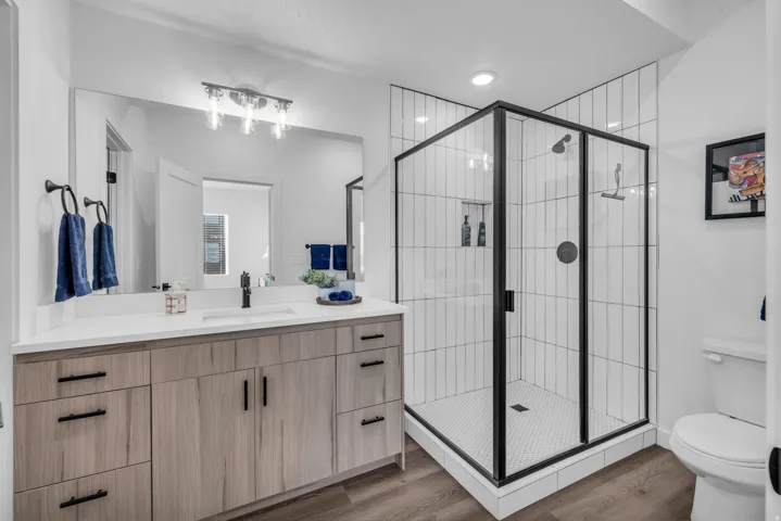 Primary bathroom with vanity, a roomy shower, and dark wood-type flooring