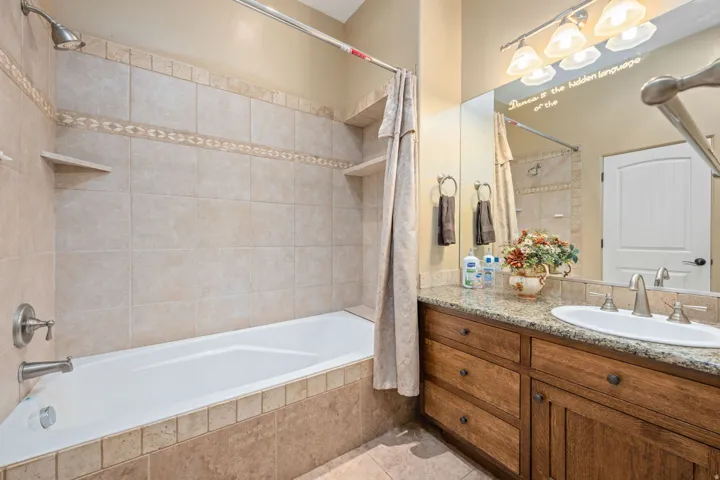 Bathroom featuring tiled shower / bath, vanity, and light tile patterned floors