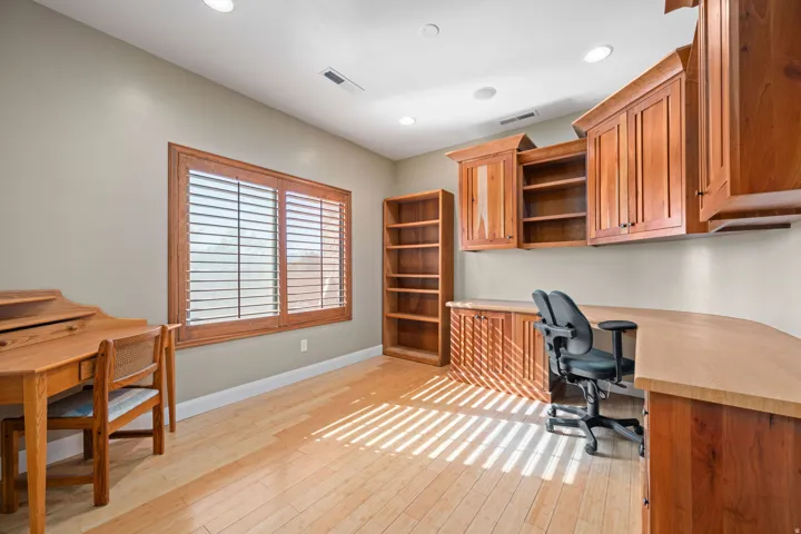 Home office with built in desk, light wood-style floors, and recessed lighting