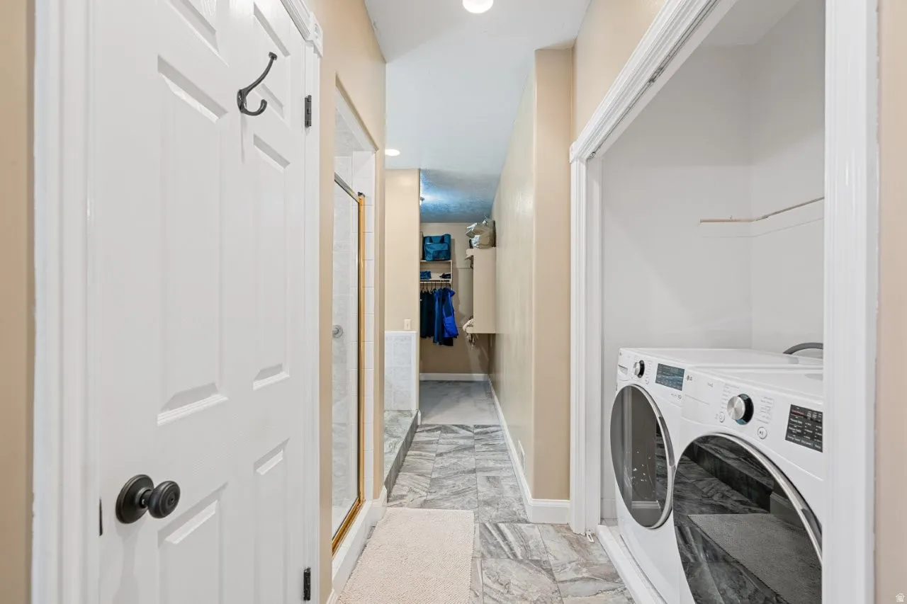 Laundry area featuring recessed lighting, light marble finish floors, and washer and clothes dryer
