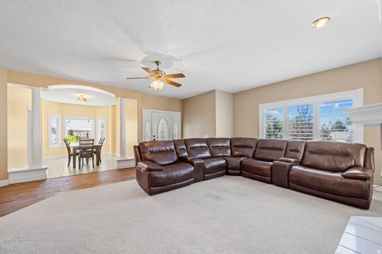 Living room with ornate columns, arched walkways, a ceiling fan, and carpet floors