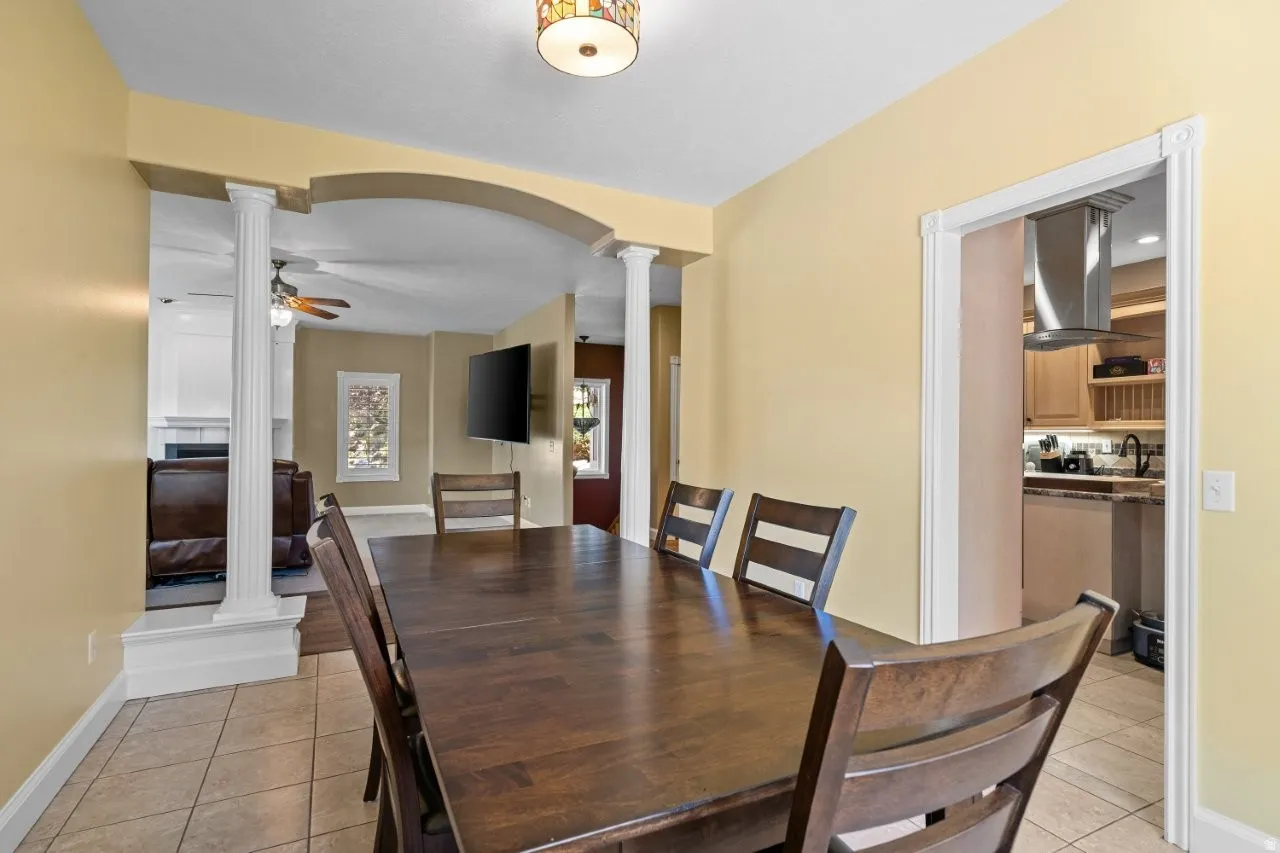 Dining area featuring ornate columns, ceiling fan, and light tile patterned floors