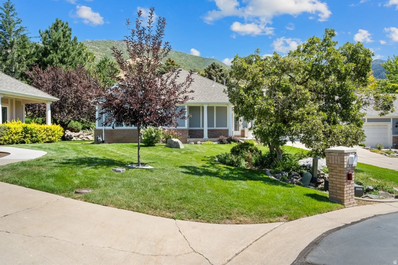 Obstructed view of property with a front yard, a mountain view, brick siding, and roof with shingles