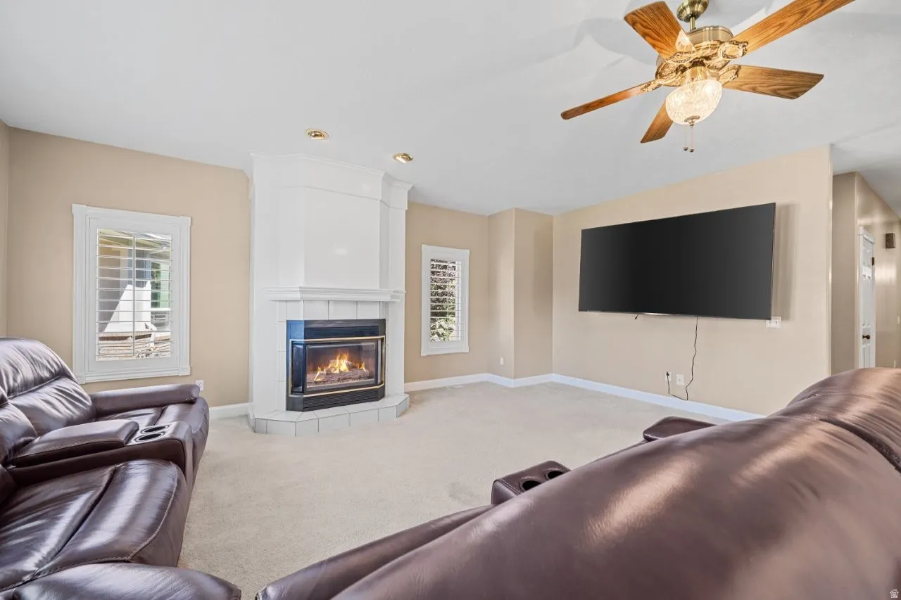 Living room with carpet flooring, a tiled fireplace, and plenty of natural light