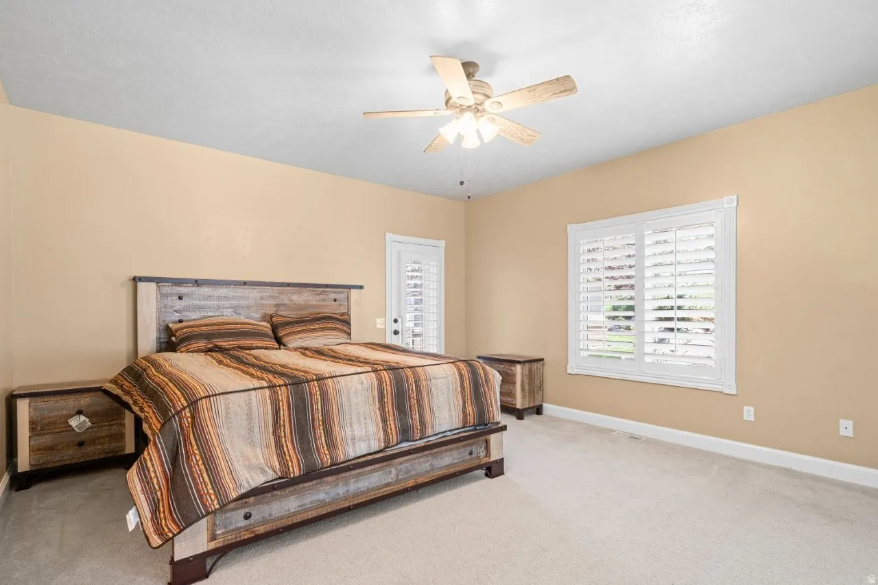 Carpeted bedroom featuring a ceiling fan and baseboards
