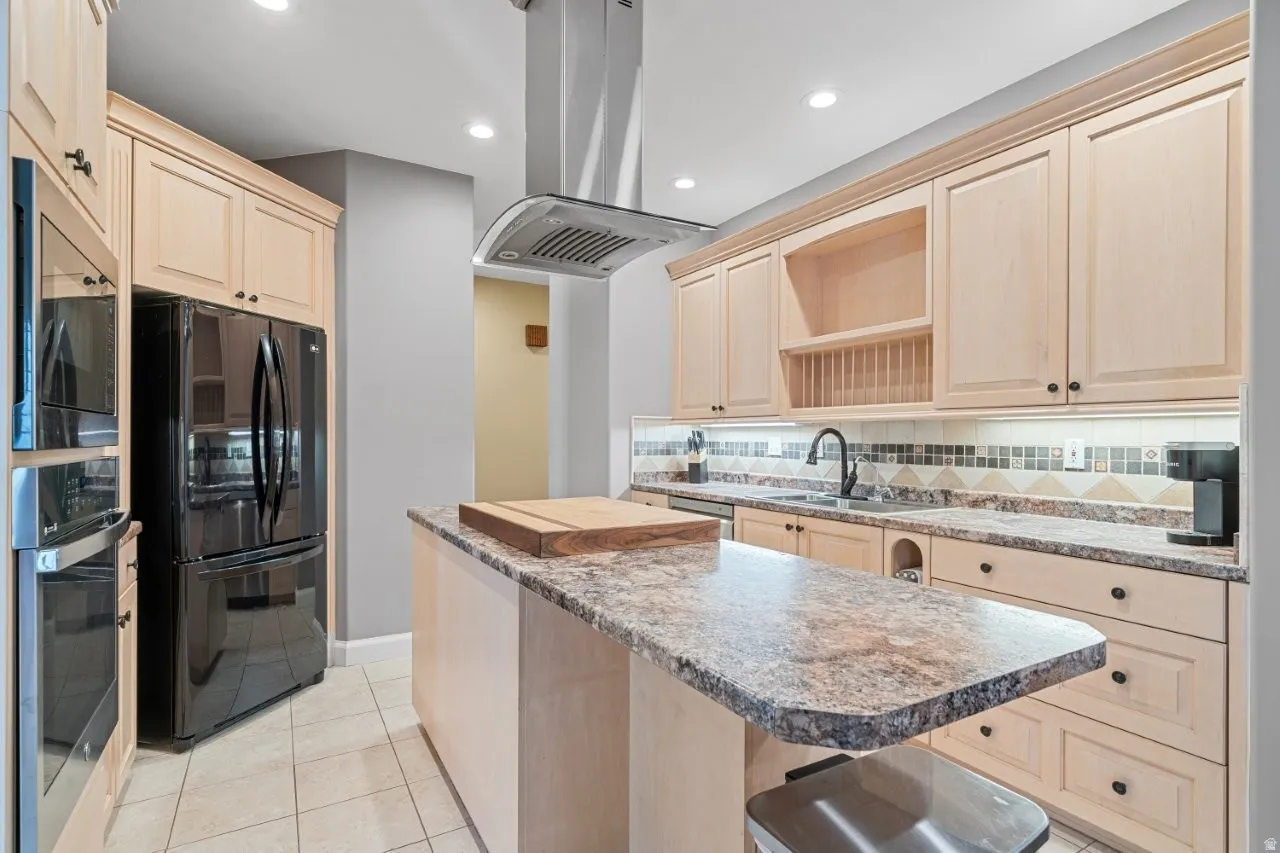 Kitchen featuring light wood finish cabinets, island exhaust hood, stainless steel appliances, open shelves, and recessed lighting