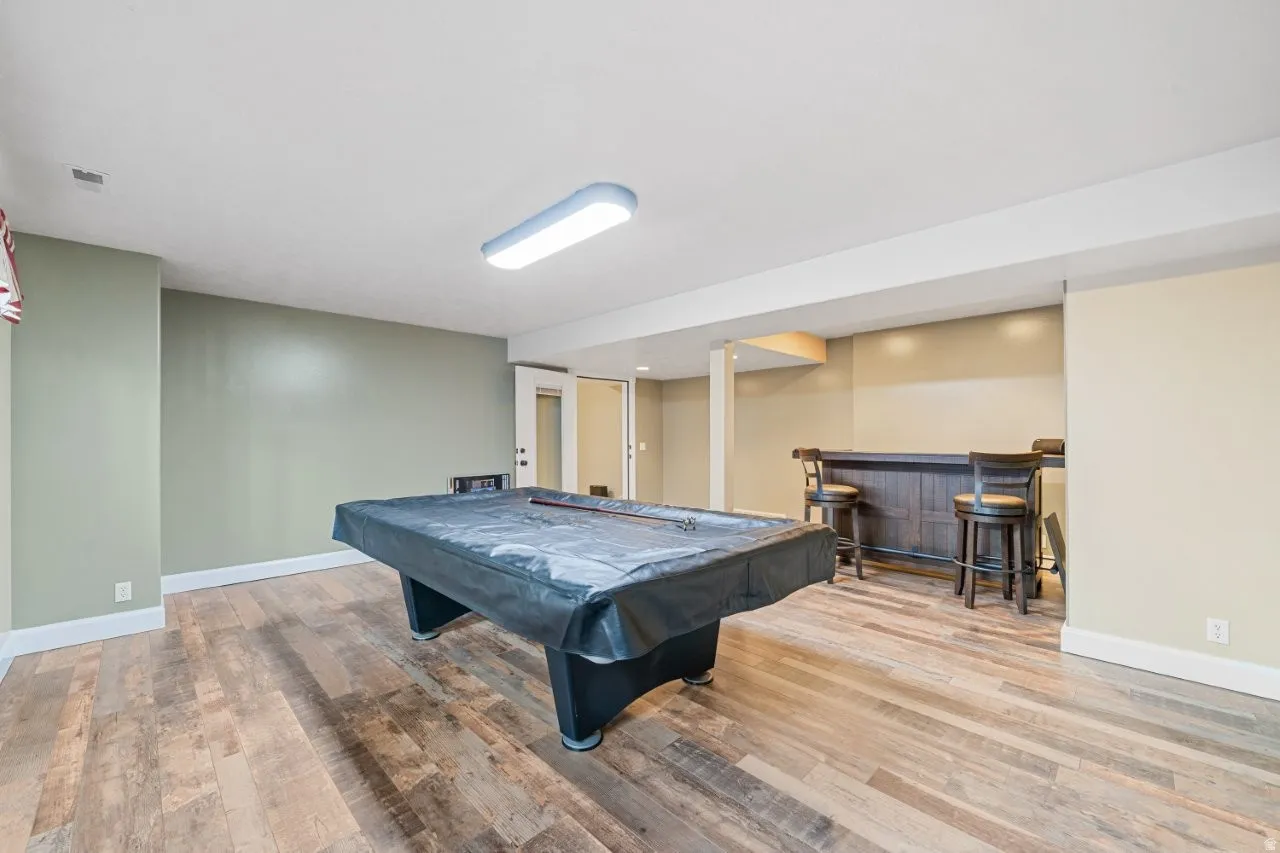 Game room featuring pool table, light wood-type flooring, and a dry bar