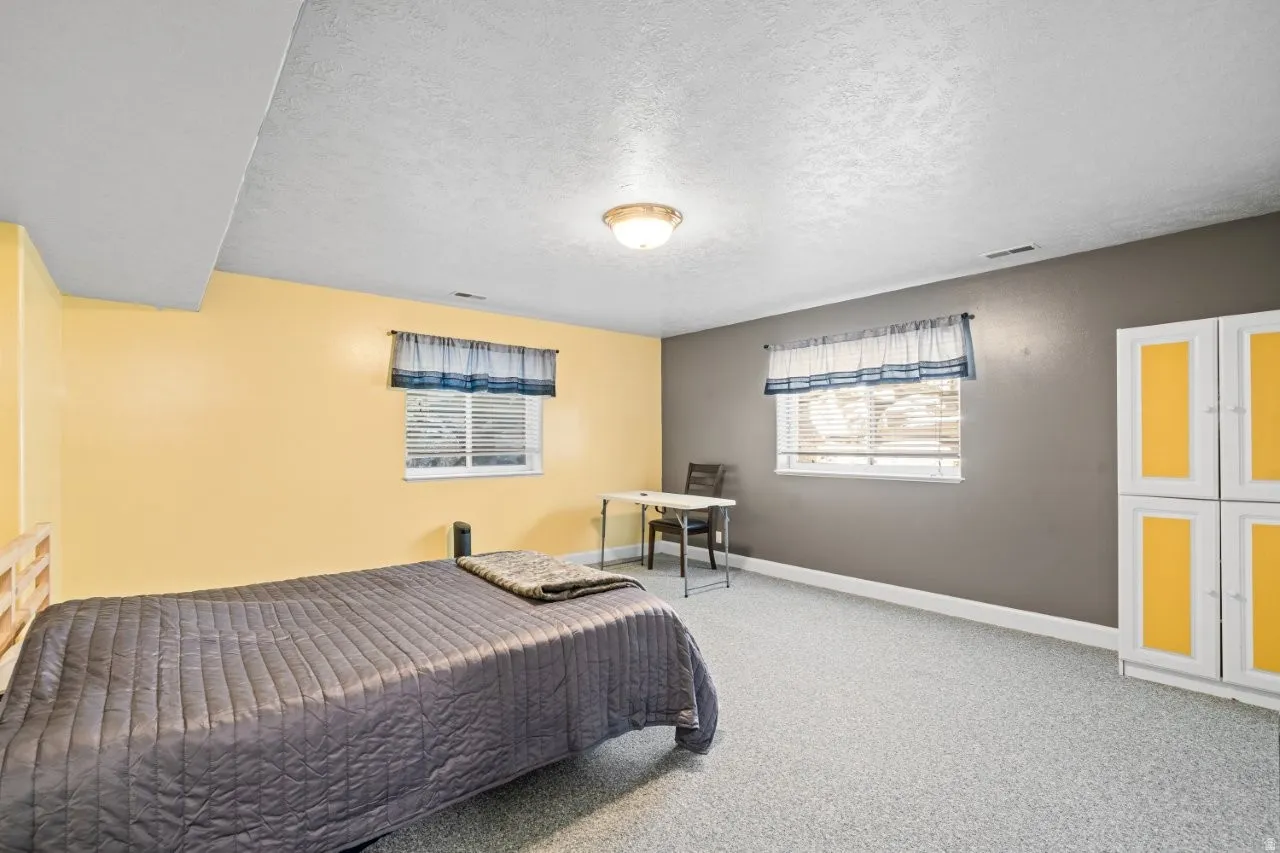 Carpeted bedroom featuring a textured ceiling and baseboards