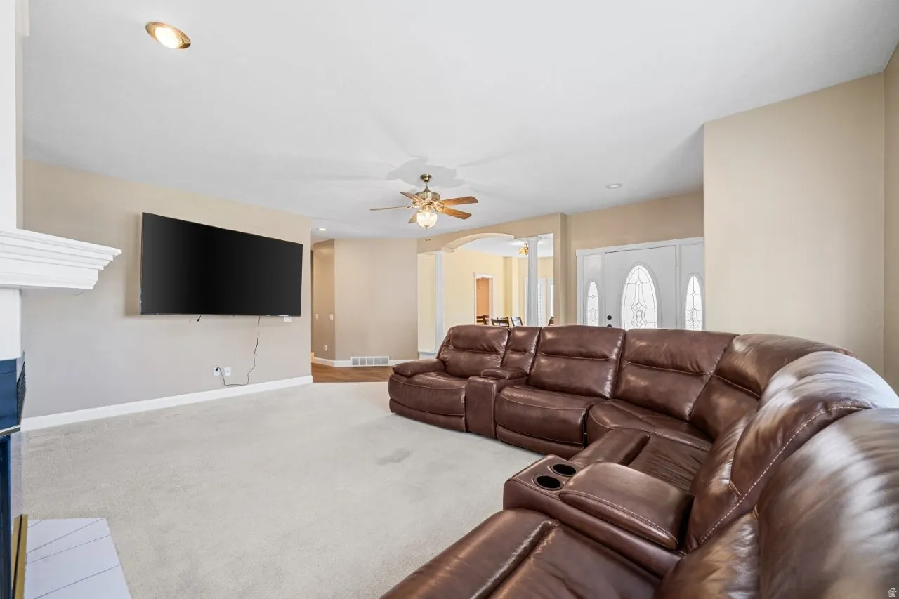 Carpeted living area featuring arched walkways and ceiling fan
