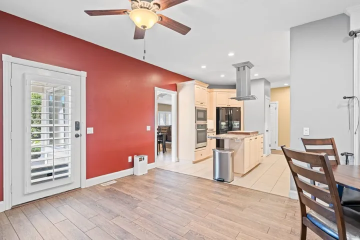 Kitchen featuring island exhaust hood, cream cabinets, a ceiling fan, stainless steel appliances, and plenty of natural light