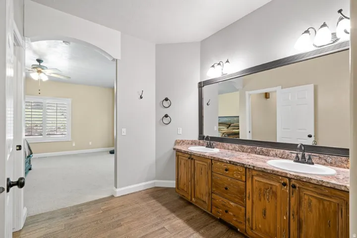 Bathroom with double vanity, light wood-style floors, and ceiling fan