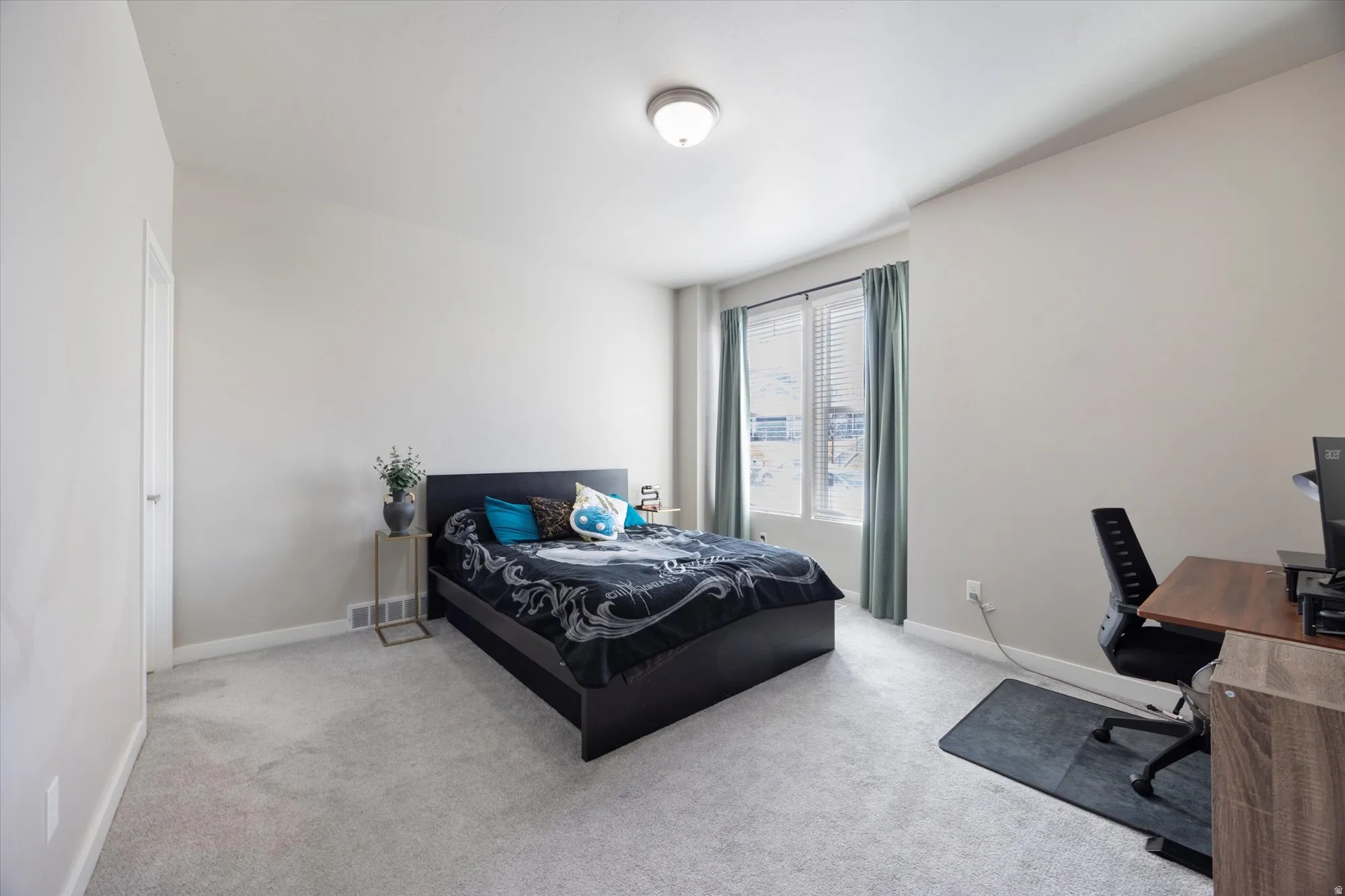 Bedroom with an office area and light colored carpet