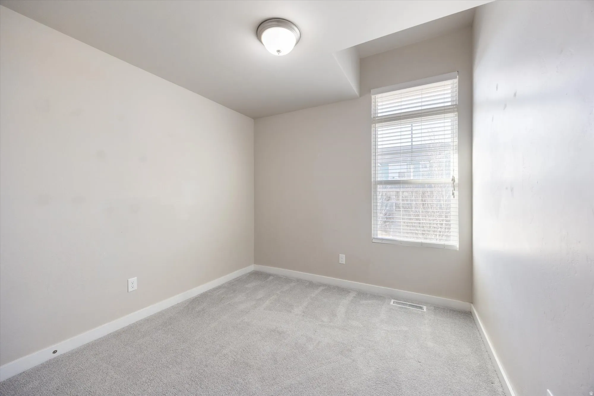 Spare room featuring light colored carpet and baseboards