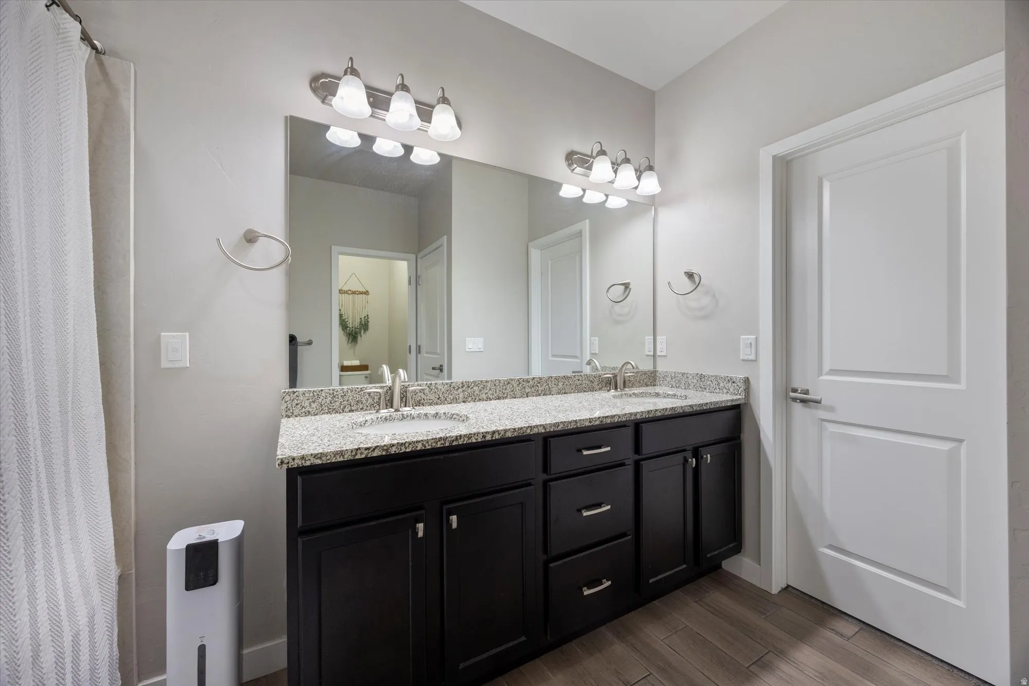Full bathroom with double vanity, curtained shower, and wood tiled floors