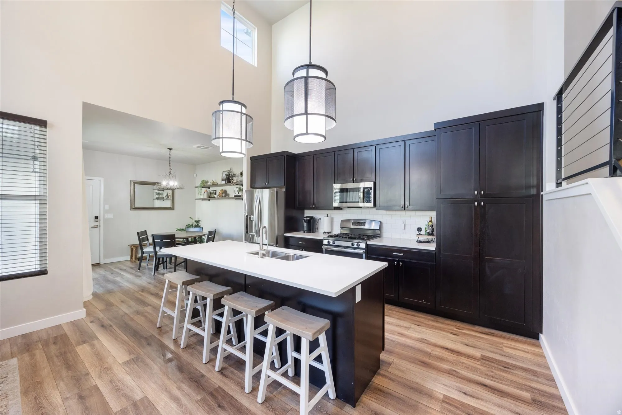 Kitchen featuring a kitchen breakfast bar, stainless steel appliances, pendant lighting, a center island with sink, and light wood-style flooring