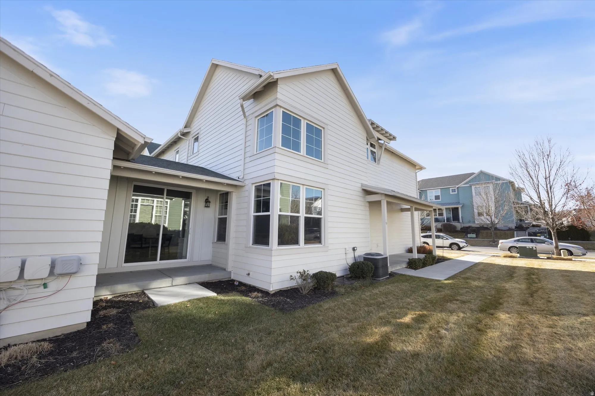 View of side of property featuring a lawn and a central AC unit