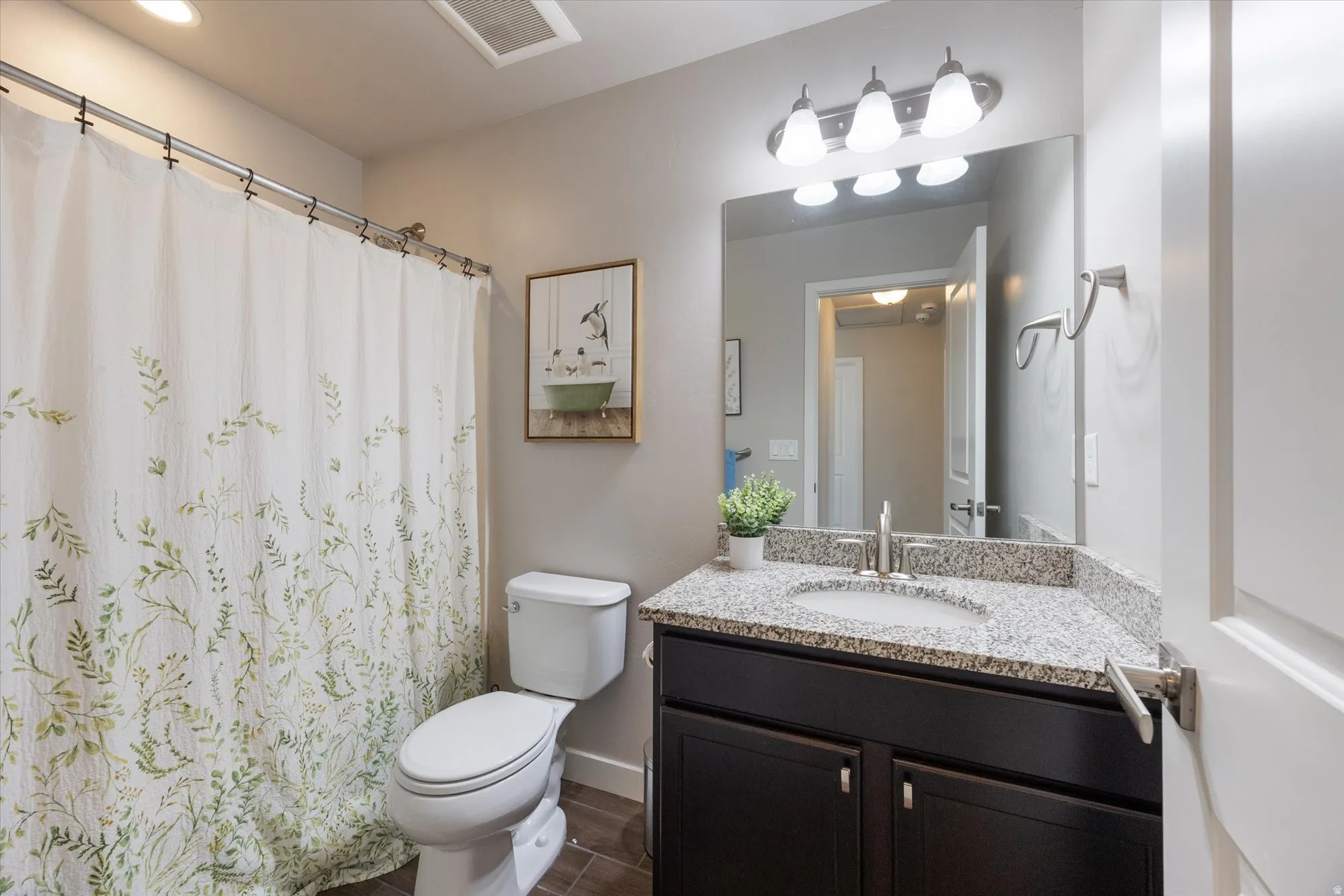 Full bathroom with vanity, curtained shower, and wood finish floors