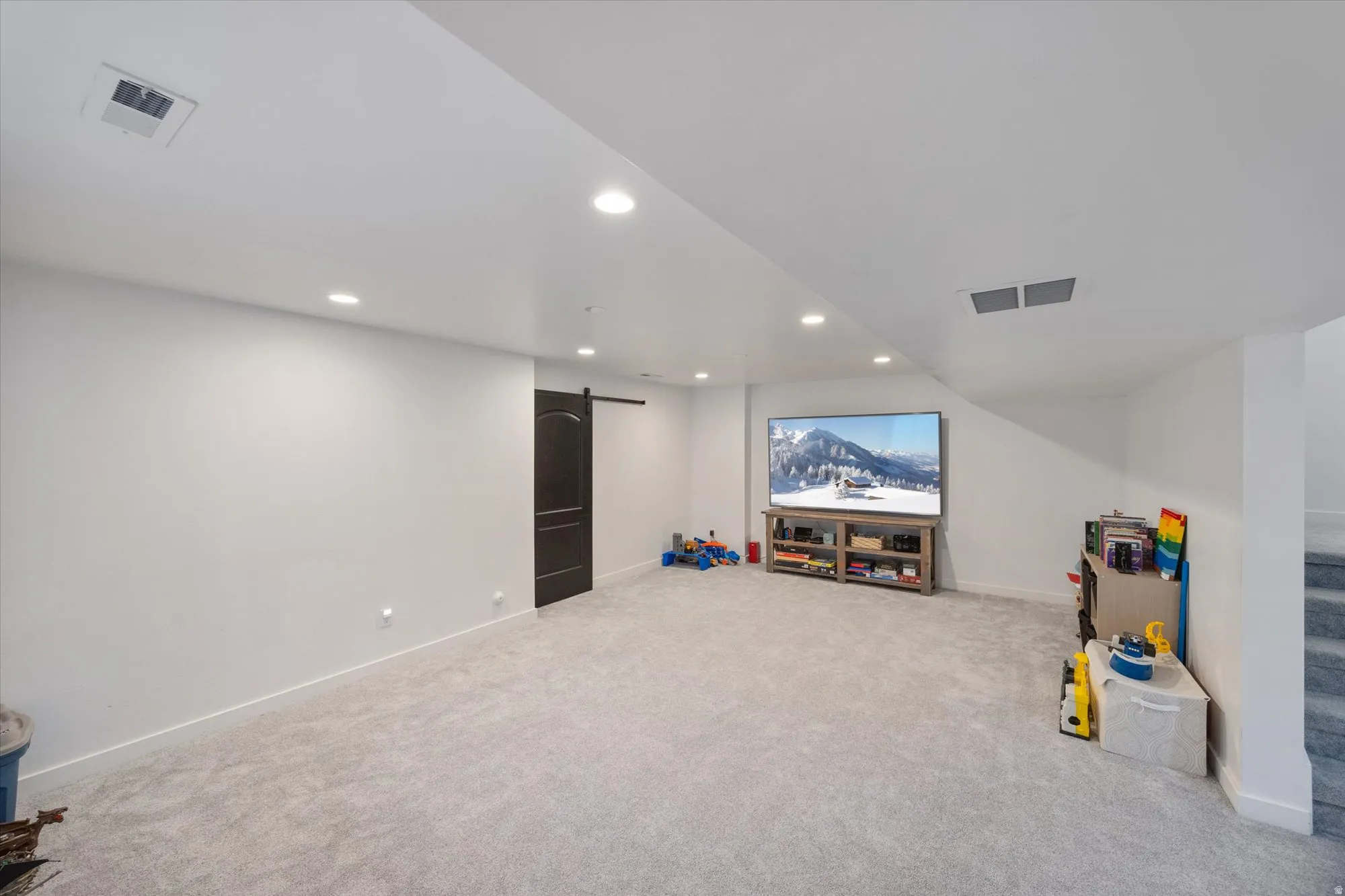 Carpeted home theater room featuring a barn door and recessed lighting