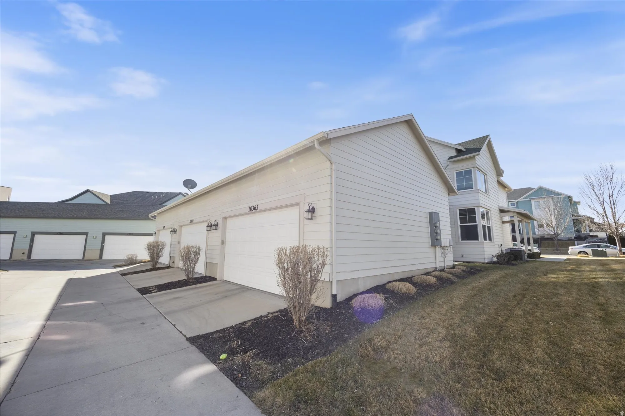 View of side of home with driveway and a lawn
