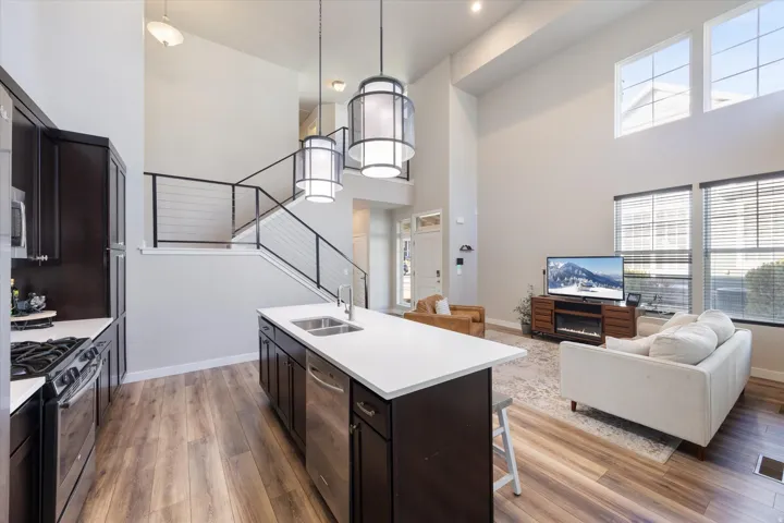 Kitchen featuring stainless steel appliances, pendant lighting, a kitchen bar, open floor plan, and light wood finished floors