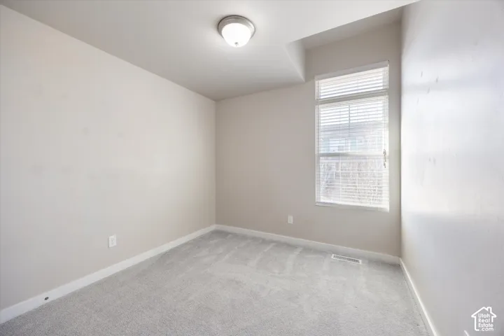 Spare room featuring light colored carpet and baseboards