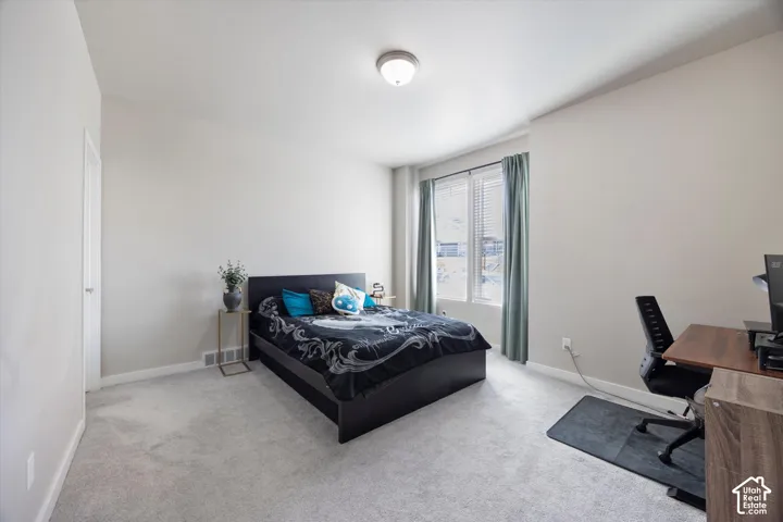 Bedroom with an office area and light colored carpet