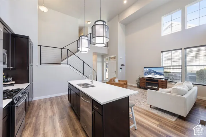 Kitchen featuring stainless steel appliances, pendant lighting, a kitchen bar, open floor plan, and light wood finished floors