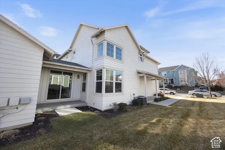 View of side of property featuring a lawn and a central AC unit